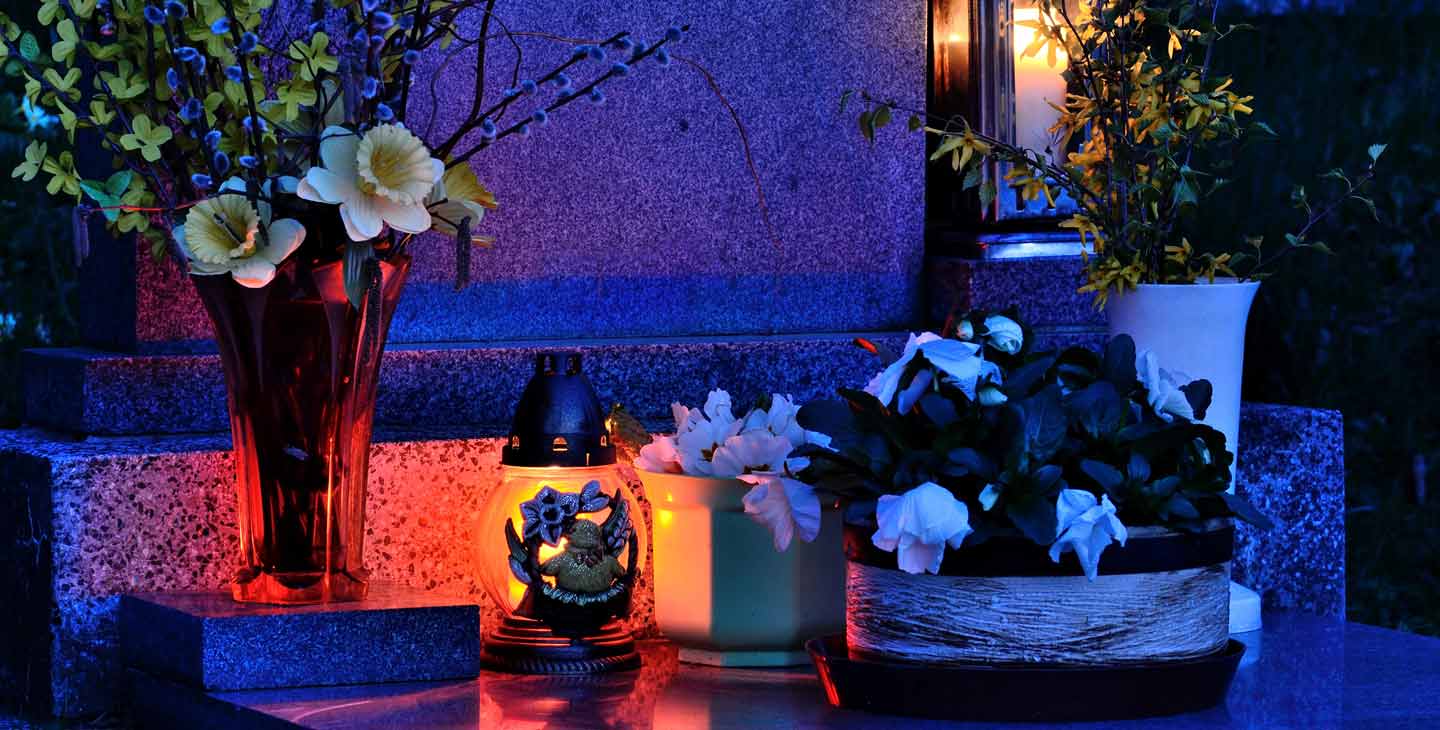 Blumen und Gedenkkerze auf einem Grab