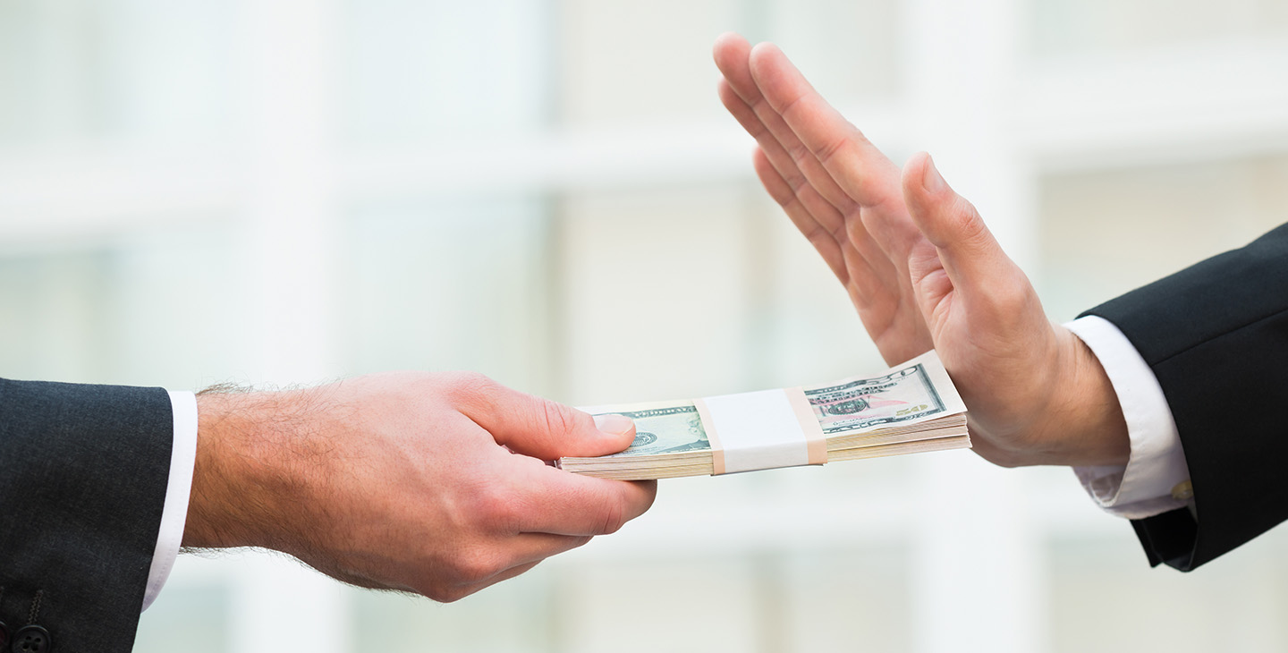 Hand streckt Bündel Geld entgegen und wird zurückgewiesen