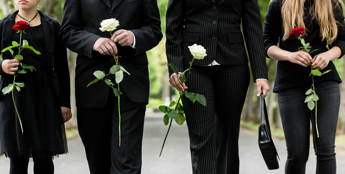 Familie in schwarz gekleidet mit weißer und roter Rote in der Hand trauern.