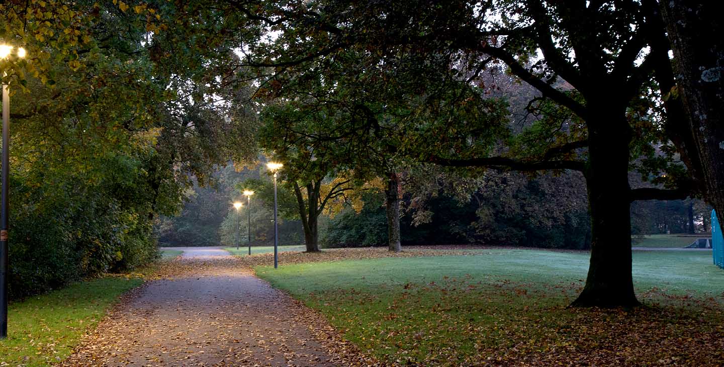 beleuchtete Straße auf einem Friedhof in der Dämmerung