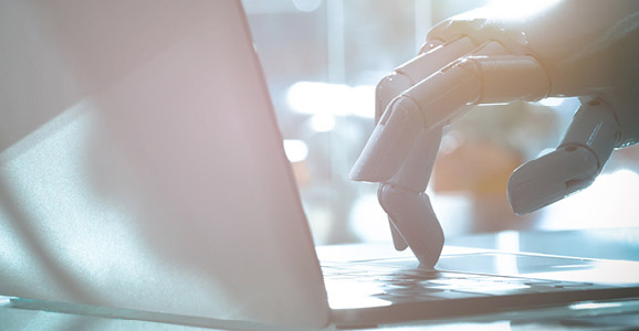 Künstliche Hand tippt in eine Laptop-Tastatur
