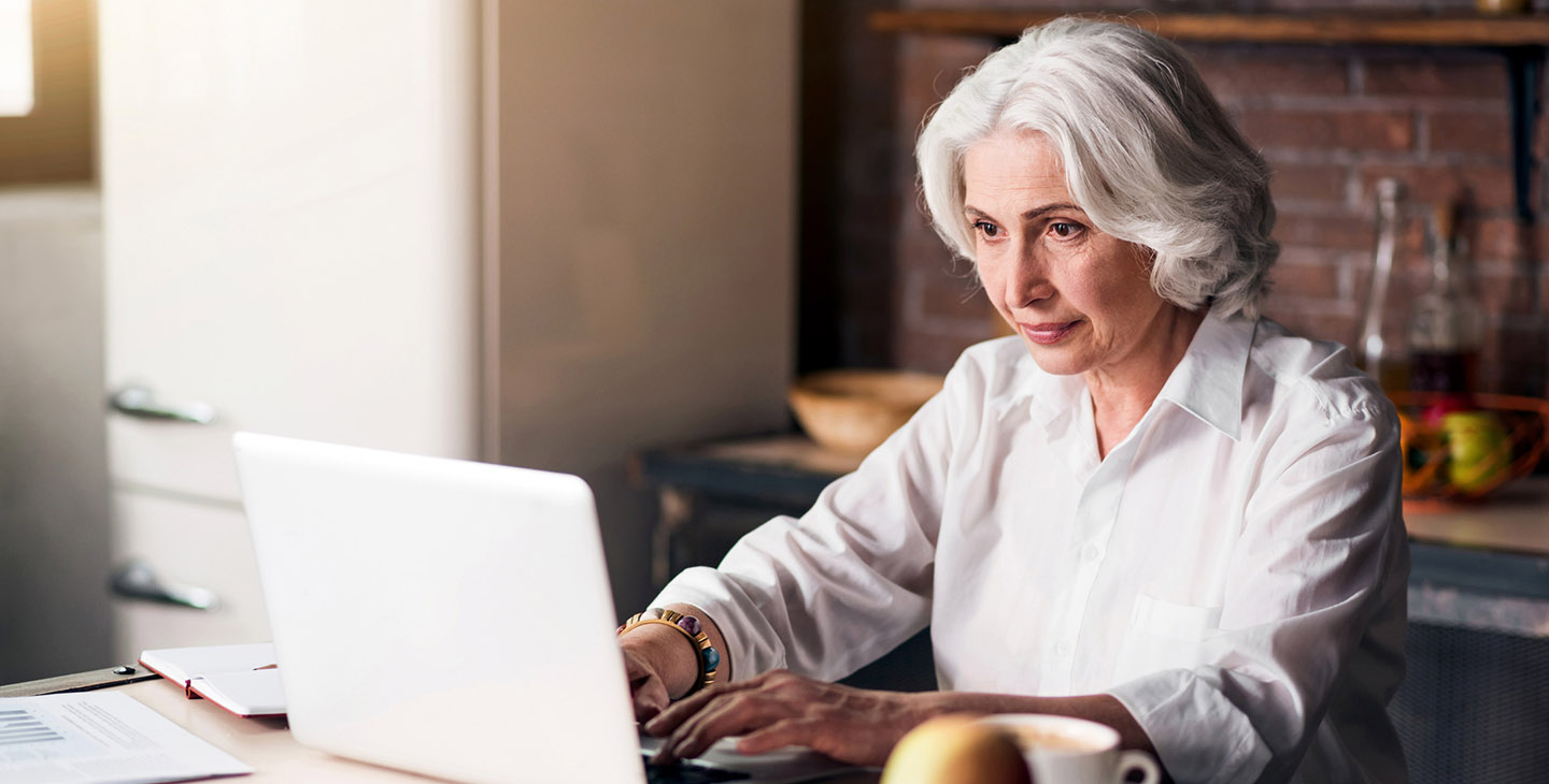 Alte, gutaussehende Dame, die ihren Laptop benutzt