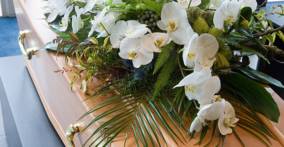 Ein Sarg mit einem Blumenarrangement in einer Leichenhalle