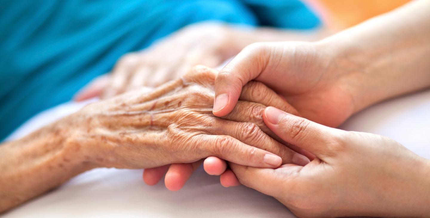 Hände junger Frau halten die Hand einer alten Frau