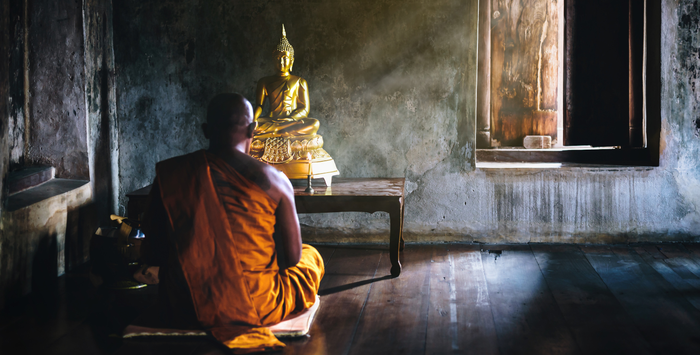 Ein Mönch meditiert vor einem Buddha