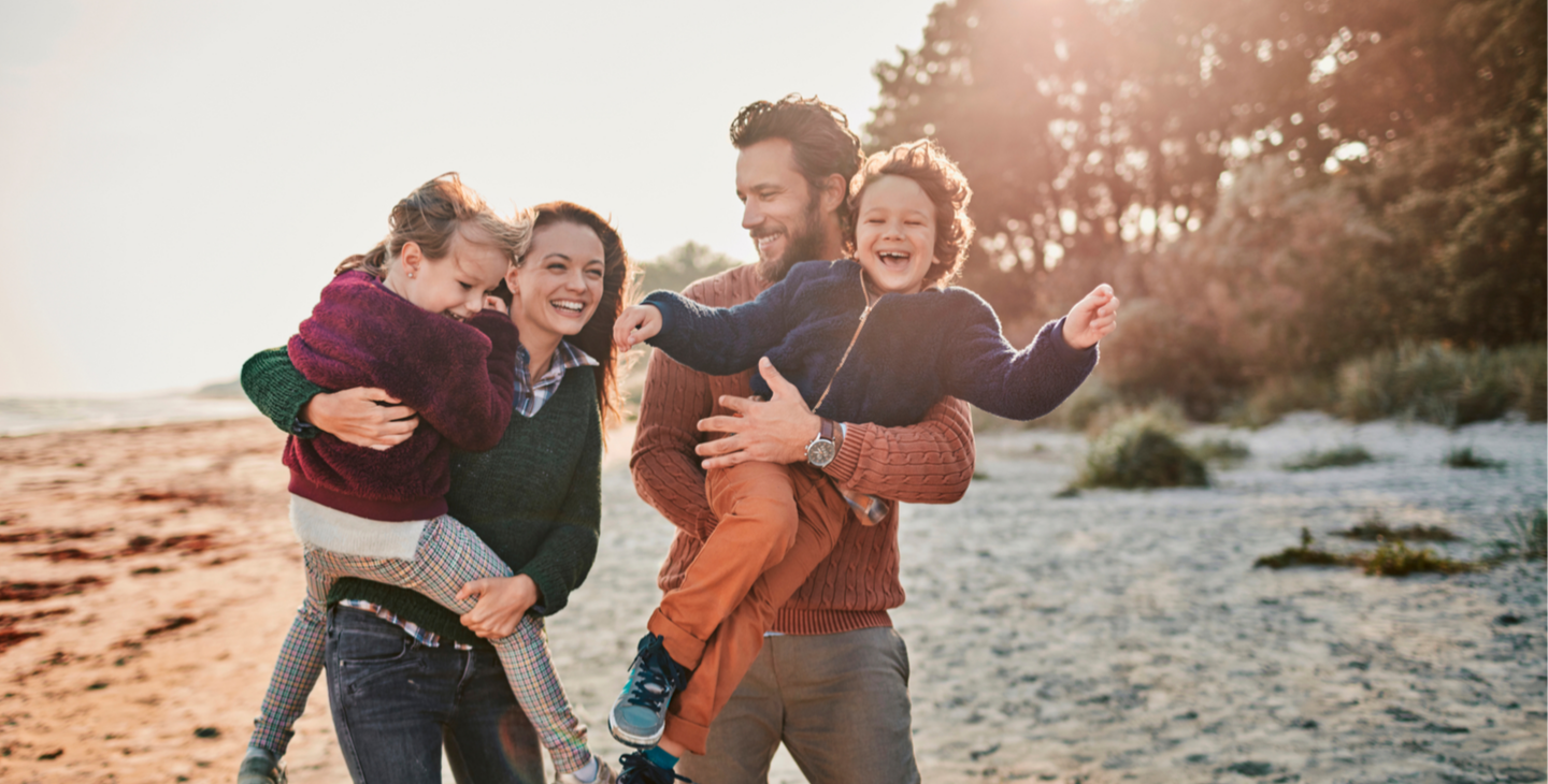 Familie in Wollpullis mit kleinen Kindern am Strand