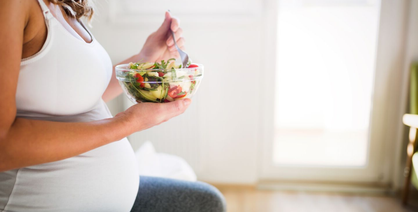 Schwangere Frau ernährt sich gesund und isst Salat