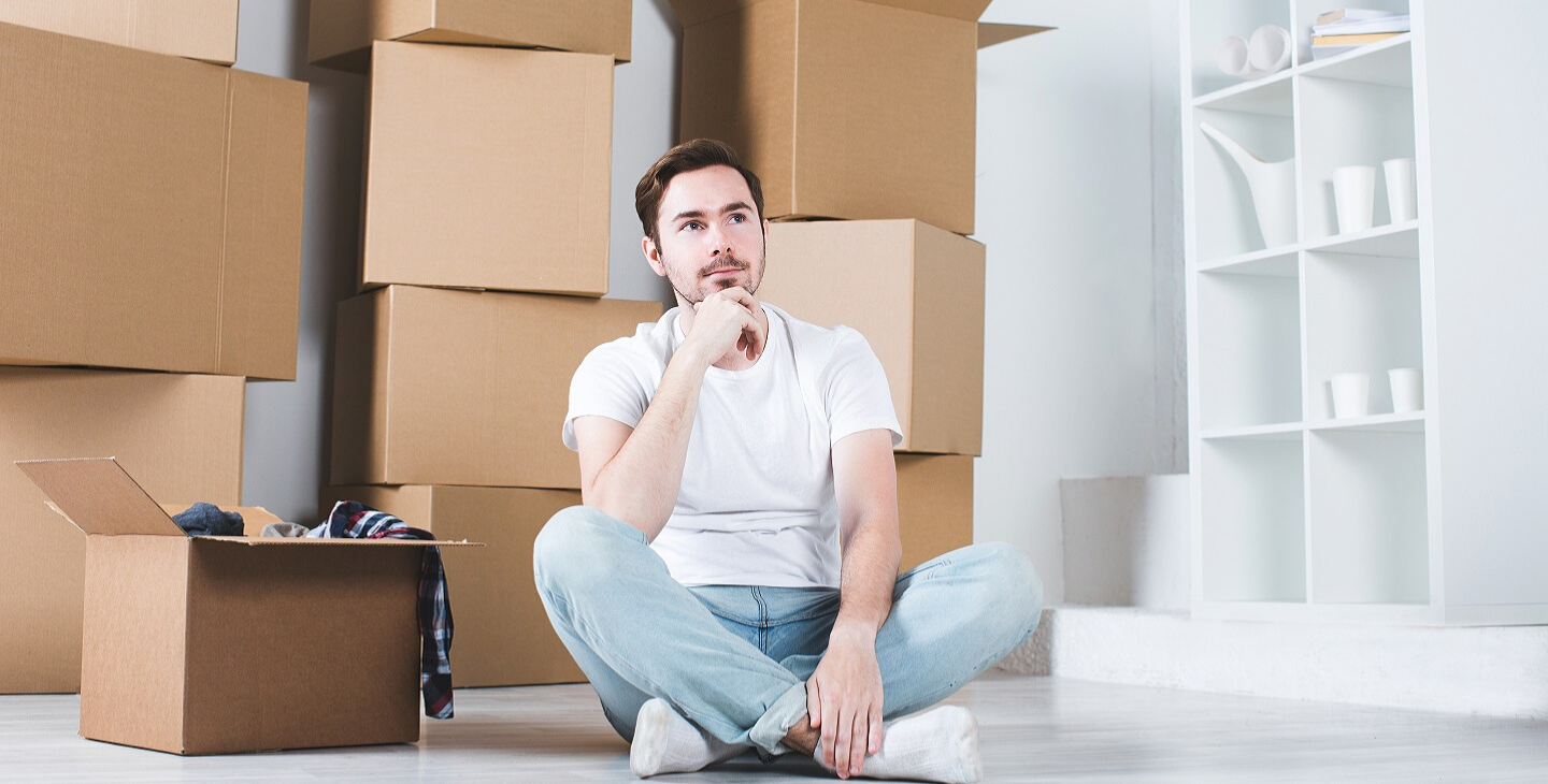 Mann sitzt fragen in einem Zimmer voller Umzugskartons
