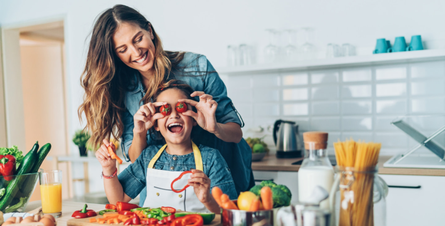 Tomaten auf den Augen bei einem Kind mit der Mama im Hintergrund