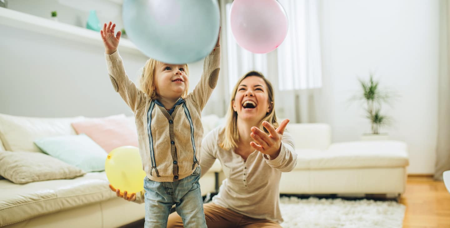 Babysitter spilt mit kleinem Kind und Luftballons