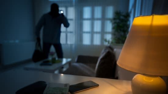 Einbrecher mit Taschenlampe in einer Wohnung
