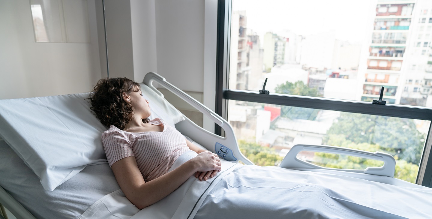 junge Frau liegt am Fenster im Krankenbett