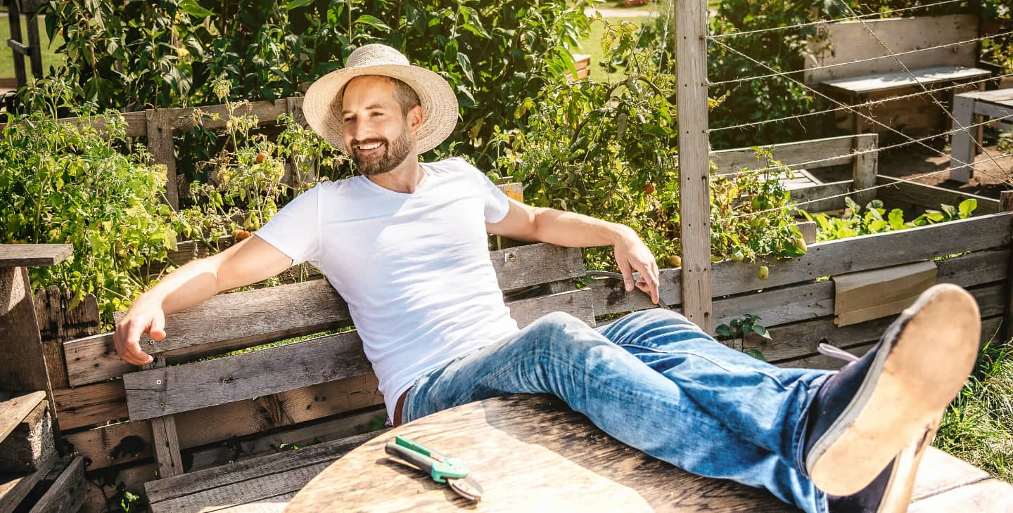 Mann mit Strohhut sonnt sich nach der Gartenarbeit