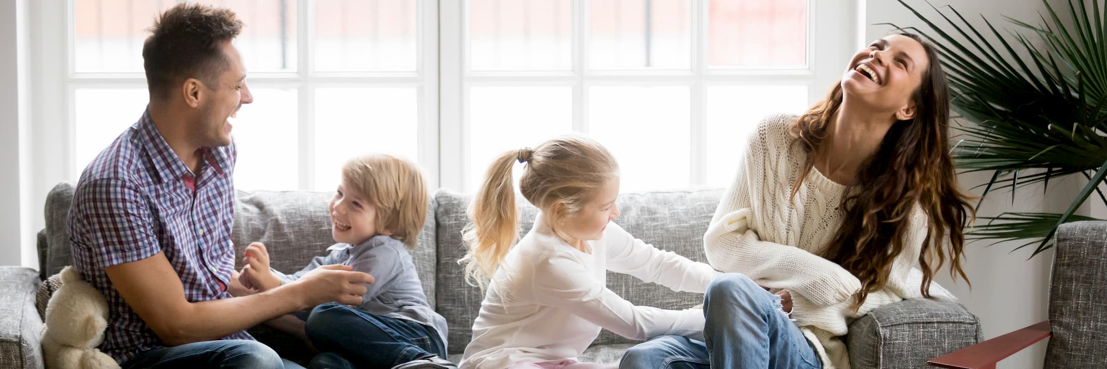 Familie lacht mit ihren beiden kleinen Kindern