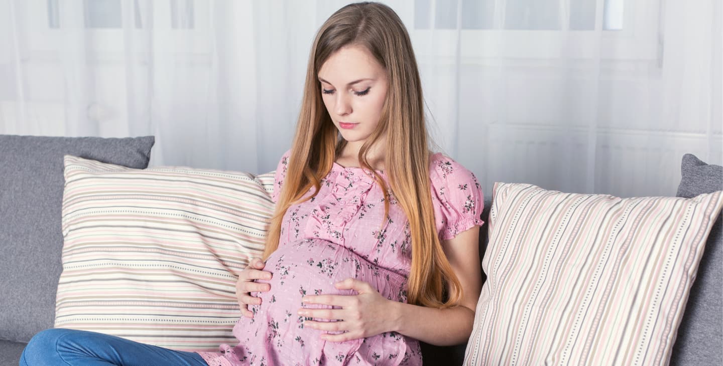 werdende Teenie Mutter schaut auf ihren Babybauch