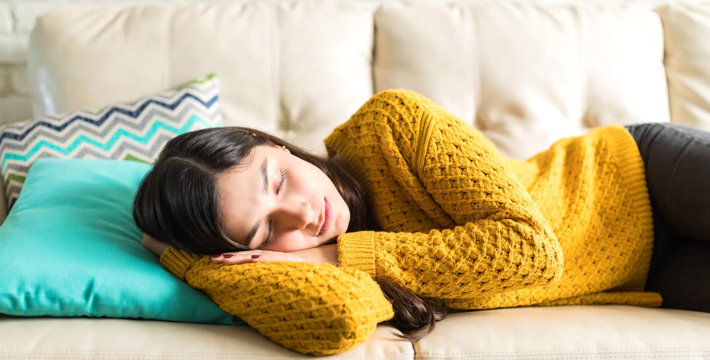 Frau mit gelbem Pulli schläft auf dem Sofa