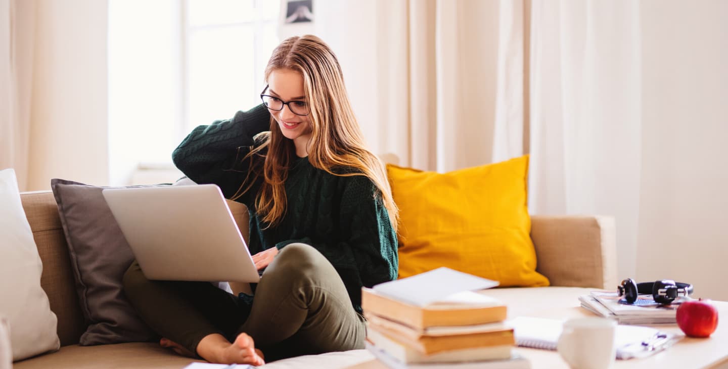 junge Frau sitzt mit Laptop auf der Couch