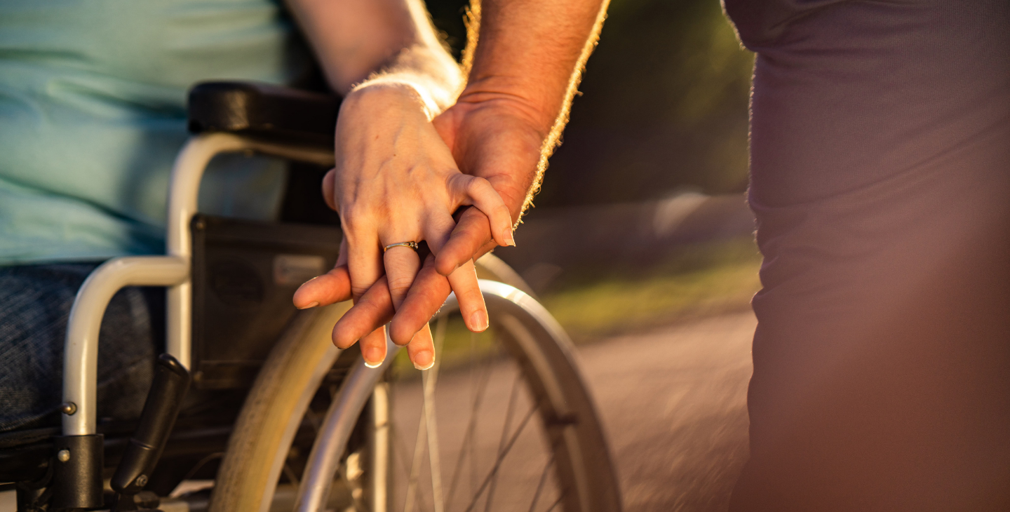 Mann hält Rollstuhlfahrer die Hand