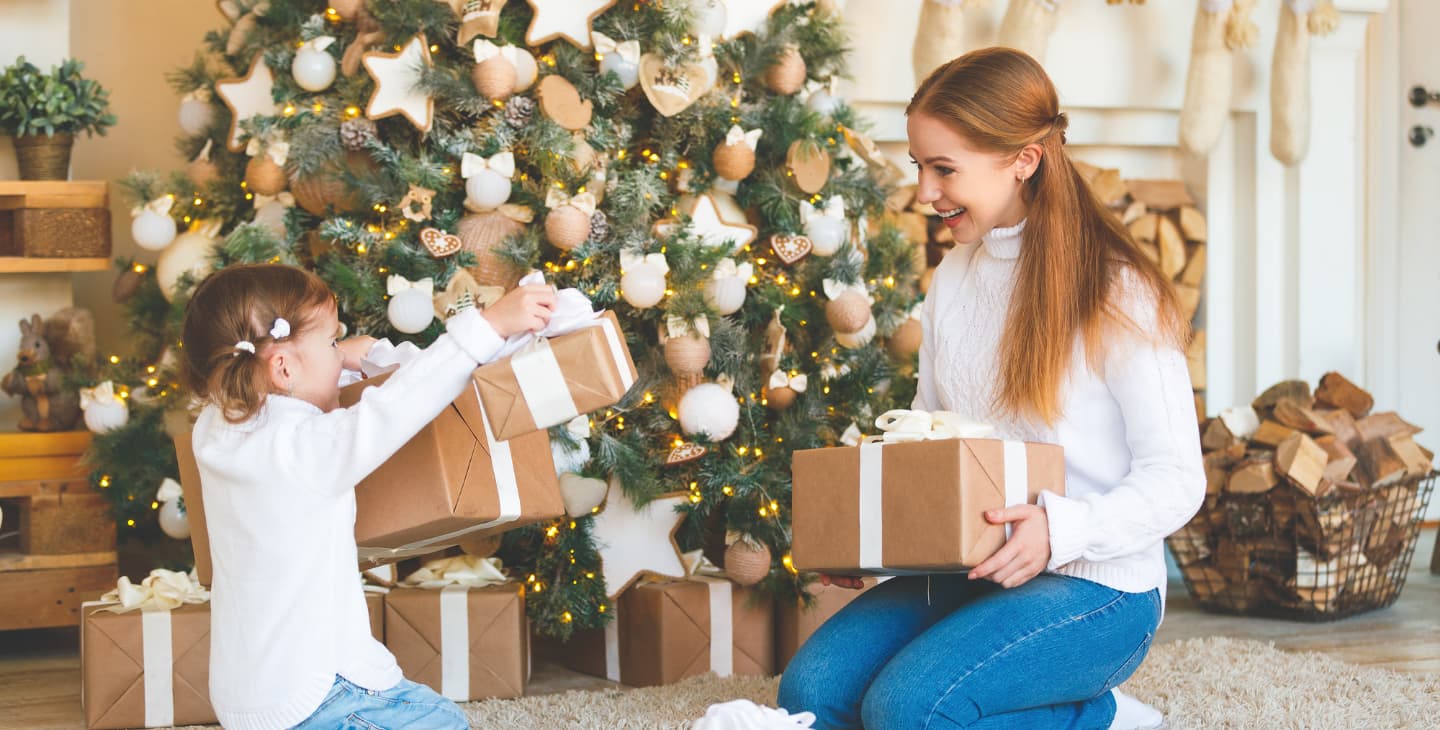 Mama und kleine Tochter bei der Bescherung unter dem Weihnachtsbaum