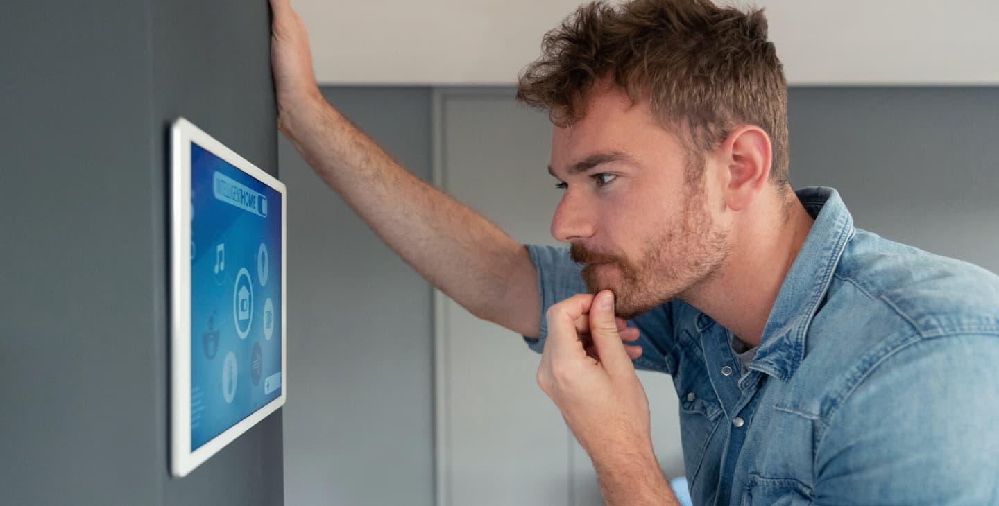 Mann steuert Smart Home über integriertes Tablet an der Wand