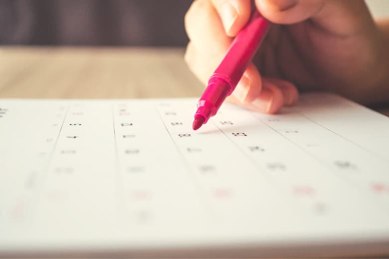 pinker Stift mit Kalender im Hintergrund