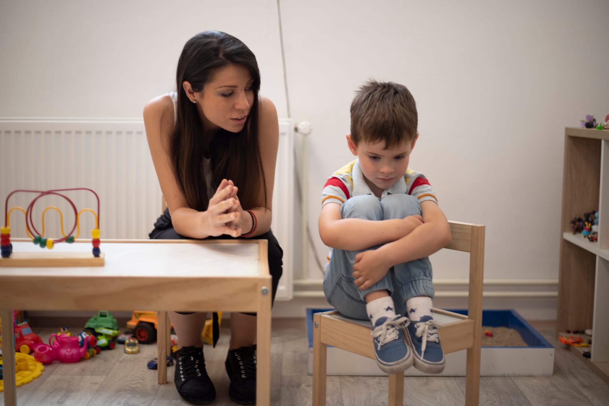 Autismus_Asperger_Diagnose - LV 1871 Kind und Erzieherin sitzen auf Stühlen