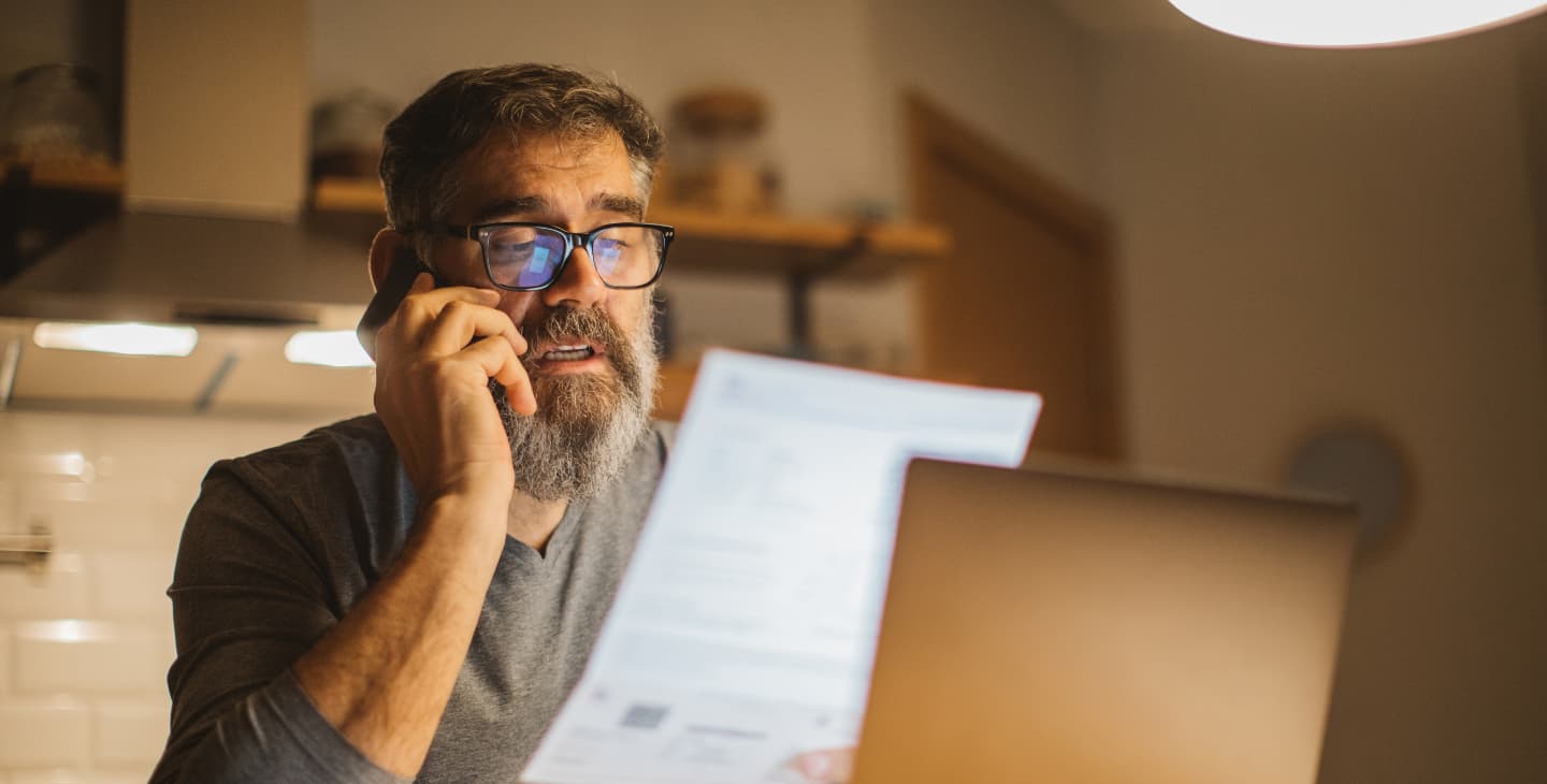 Rentner sitzt vor seiner Steuererklärung und telefoniert