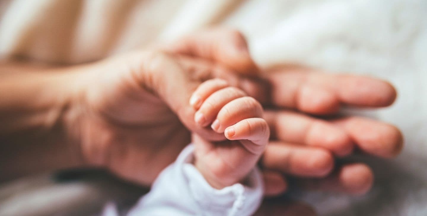 babyhand hält den Daumen von Mama