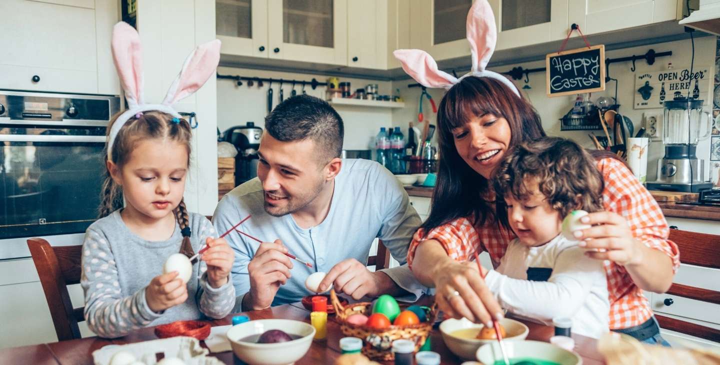 Junge Familie bemalt Ostereier mit ihren kleinen Kindern