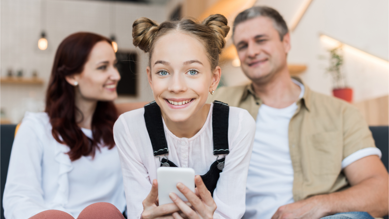 Teenager lächelt mit dem Smartphone in der Hand