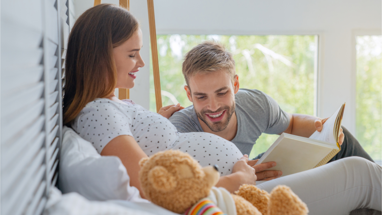 Werdender Vater liest dem Baby im Babybauch ein Buch vor