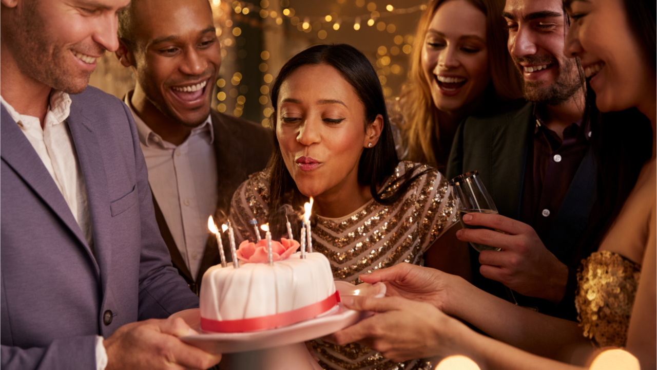 Frau feiert Geburtstag und bläst Kerze auf Torte aus