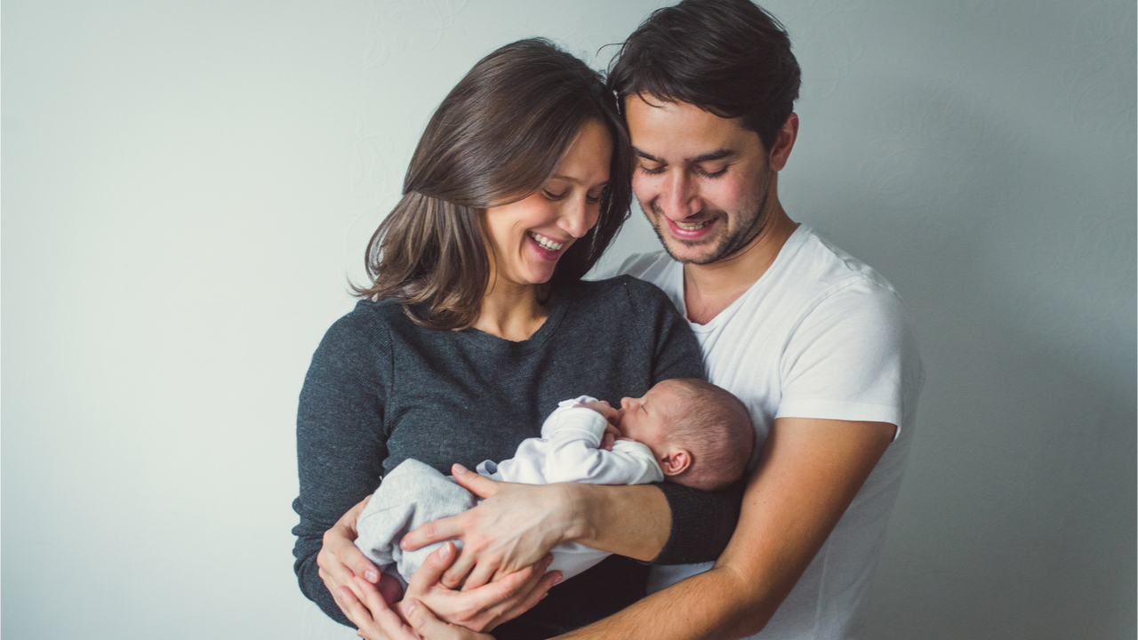 junge Eltern halten ihr neugeborenes Baby in den Armen