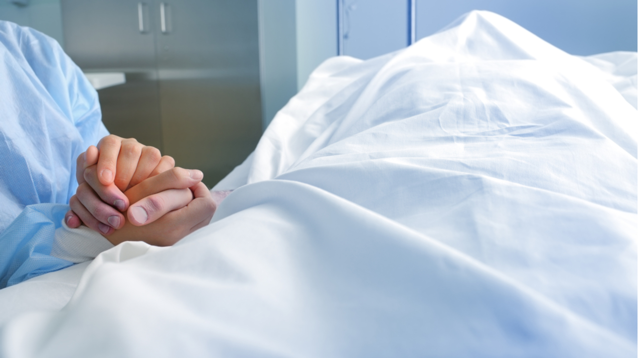 Frauenhand hält Hand eines leichnams mit Tuch über dem Kopf