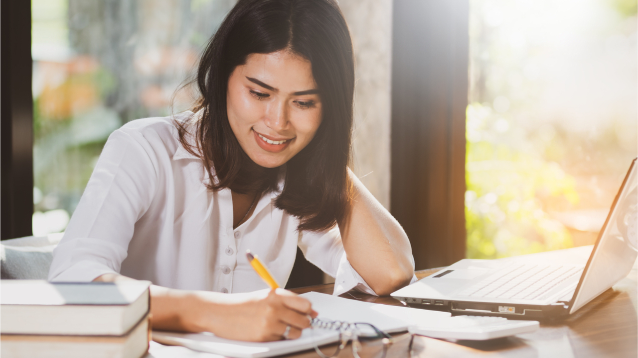 junge Frau lernt mit Stift und Block und Laptop