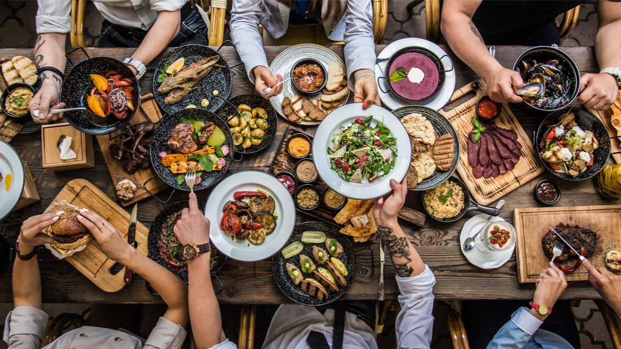 aus der Vogelperspektive Tisch mit vielen Pfannen und Tellern voller Essen