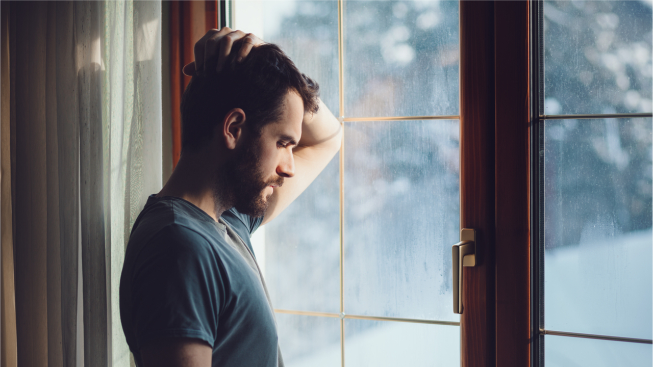 Mann schaut nachdenklich aus dem Fenster