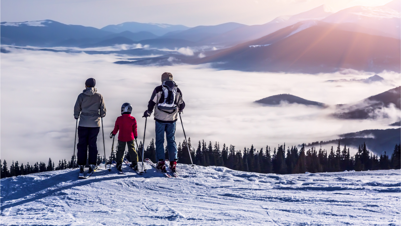 Skifahrer stehen in den Bergen und blicken in nebliges Tal