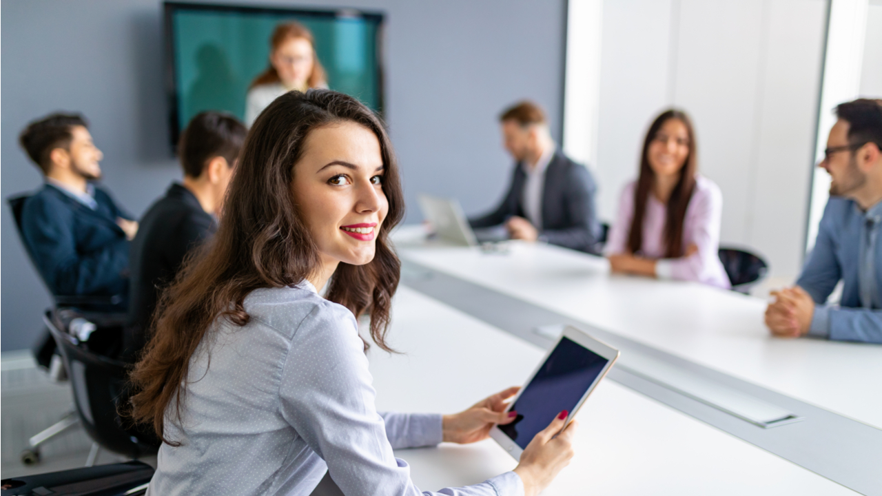 Frau mit rotem Lippenstift und Tablet in der Hand in einem Business-Meeting