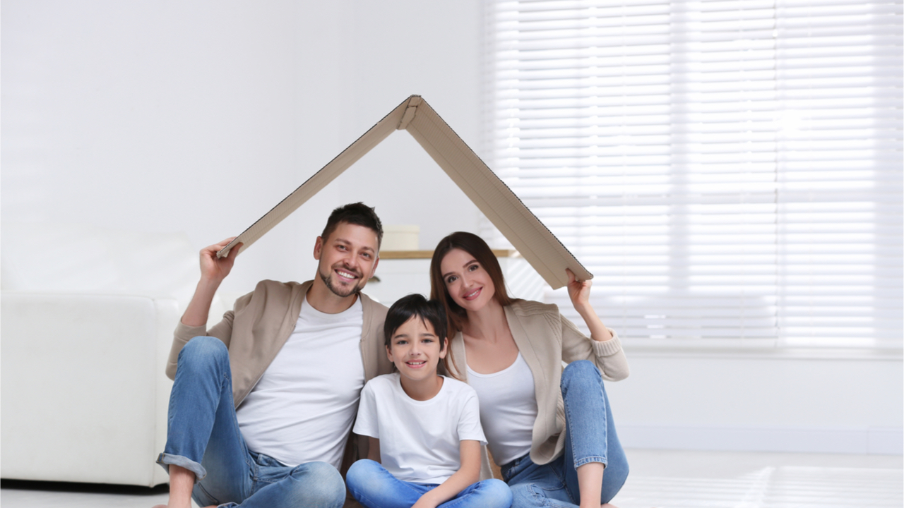 Familie mit Kind hält Karton über die Köpfe