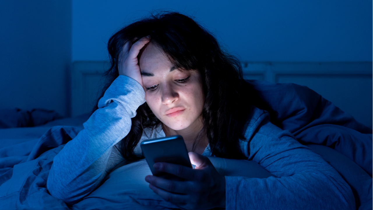 Frau im Bett surft am Smartphone
