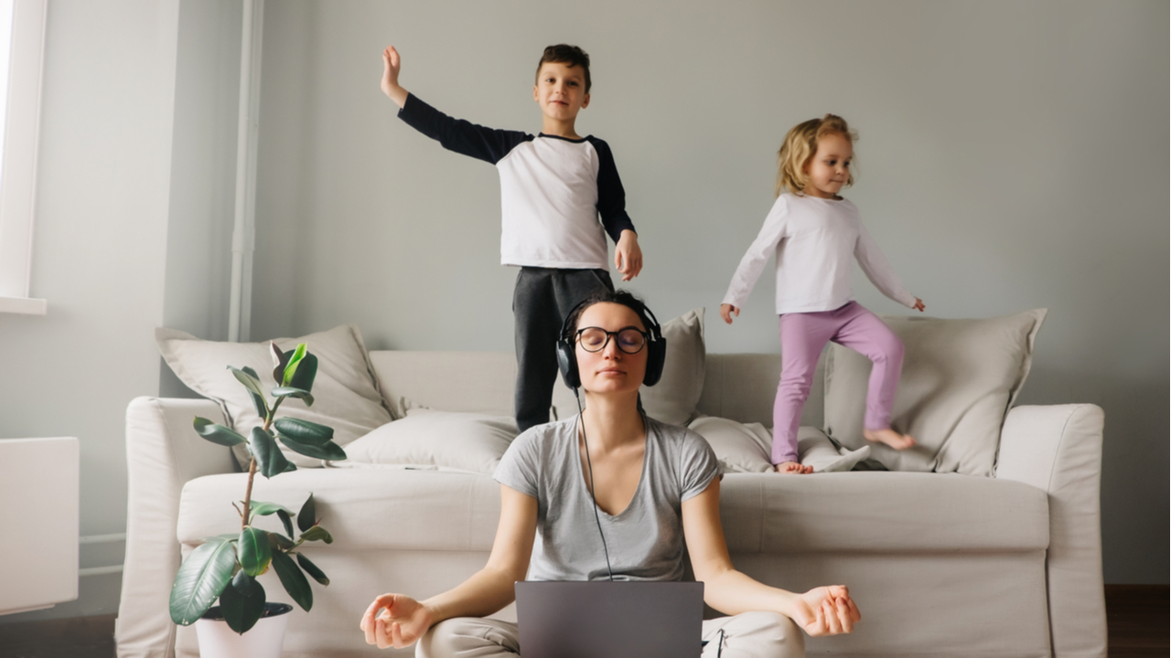 Frau im Homeoffice während Kinder im Hintergrund spielen
