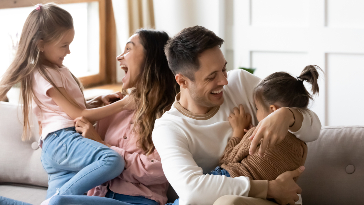 Paar mit kleinen Kindern fröhlich auf dem Sofa