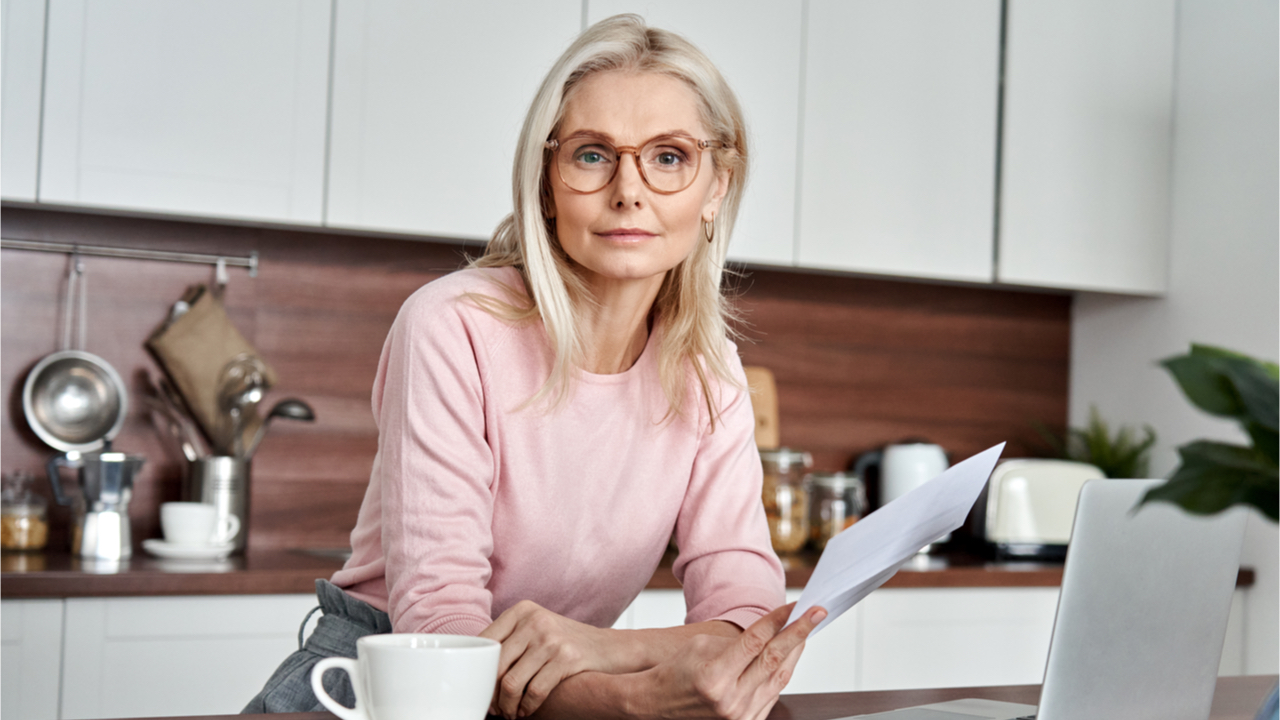 Frau in der Küche mit Latop und Brief