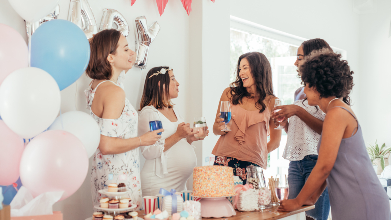Frauen feiern Babyparty mit Luftballons und Kuchen