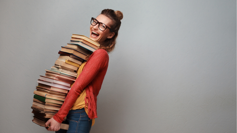 junge Frau trägt sehr viele Bücher