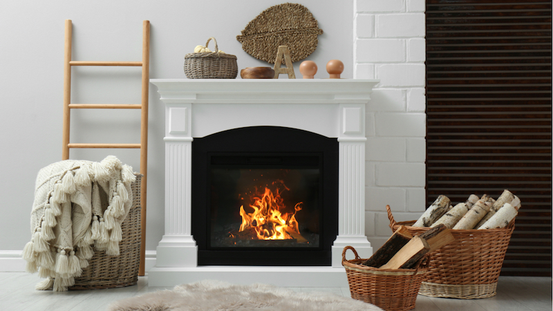 Kamin flackert mit Holzkörben im Vordergrund