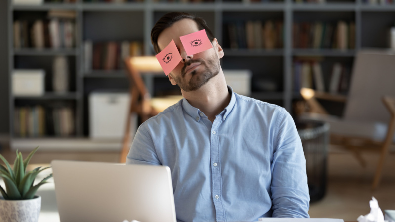 Angestellter klebt sich Papieraugen auf die Augen
