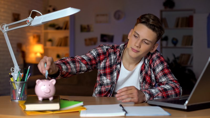Schüler steckt einen Schein in ein Sparschwein