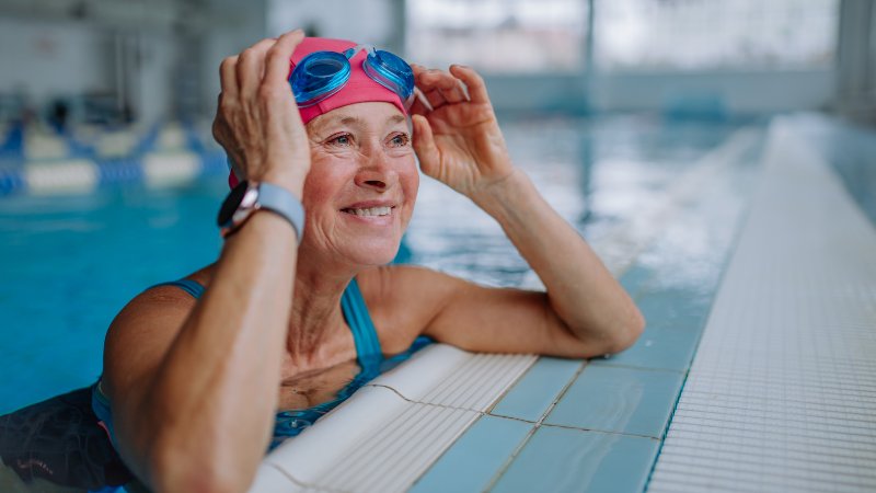 Rentnerin am Beckenrand mit Schwimmbrille und Badekappe